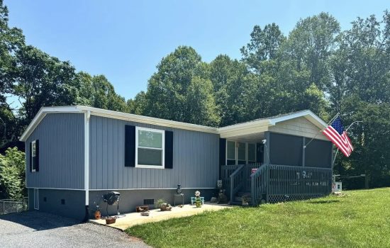 Home with light blue-grey lap siding, black shutters and a covered porch